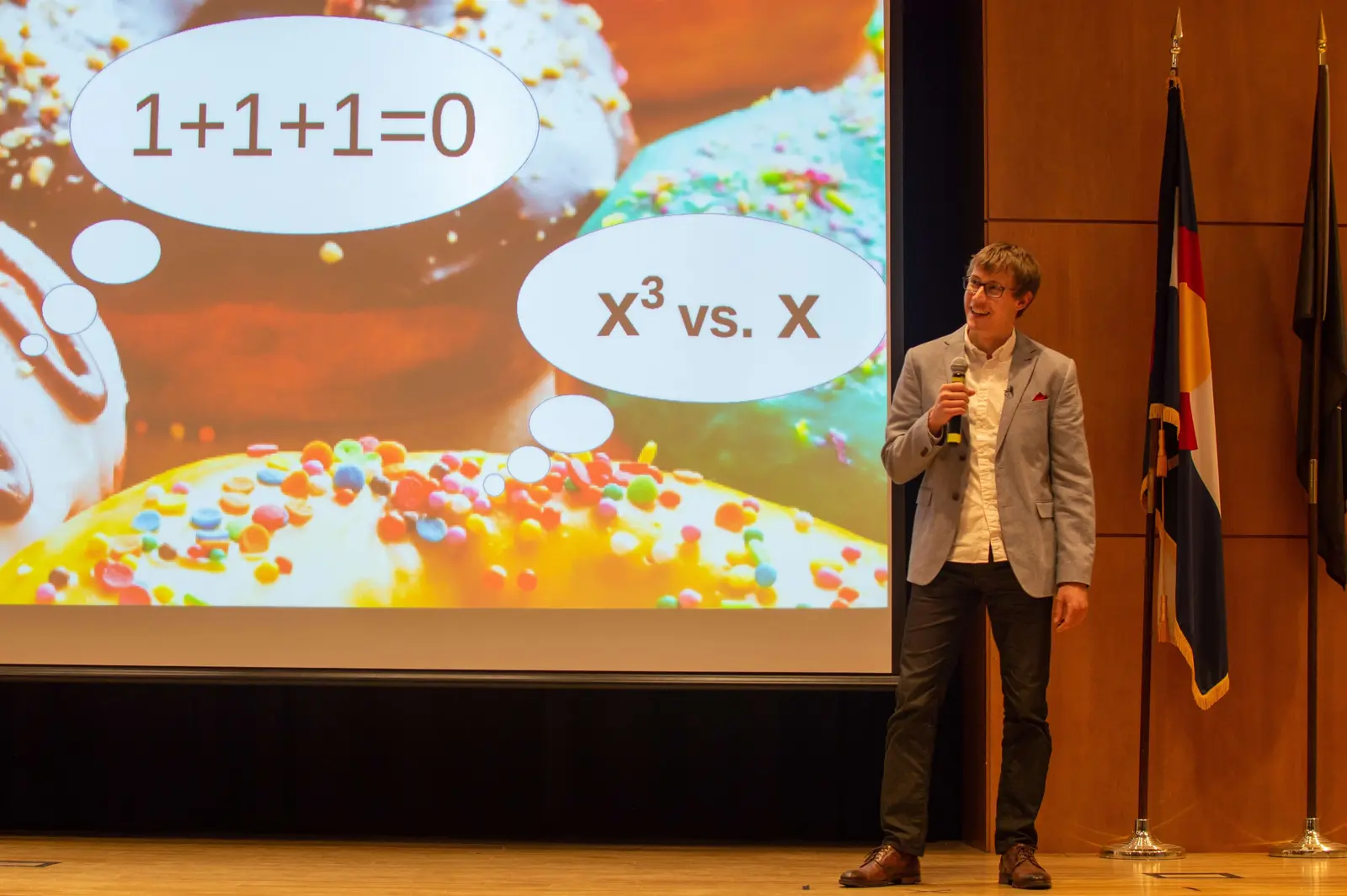 Hanson Smith presenting his three-minute thesis about monogenicity using a slide with colorful donuts
